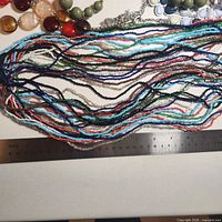 Assortment of jewellery with ruler showing scale; focus on multi-strand seed-bead necklace