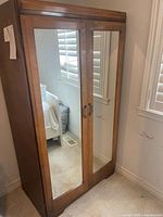Front view of wooden cupboard with mirrored doors