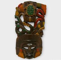 Front view of carved wooden Mayan warrior mask with painted turtle and snake details