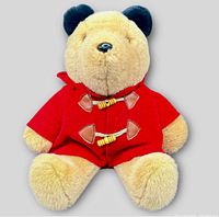 Front view of tan plush bear in red hooded coat