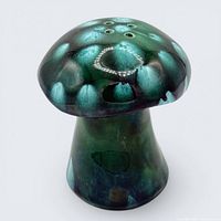 Front view of green drip glaze ceramic mushroom shaker showing cap and stem