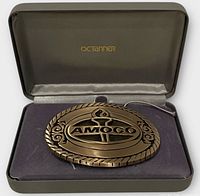 Belt buckle in presentation case, lid open showing OCTanner logo