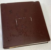 Closed brown binder album marked "I"