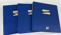 Three blue USPS commemorative stamp binders