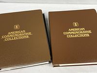 Two brown USPS American Commemorative Collections binders closed