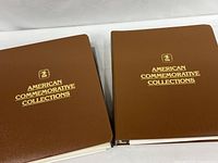 Two brown vinyl binders with gold lettering shown closed