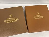 Two brown American Commemorative Collections binders closed, showing covers