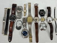 Group shot of 13 wristwatches and separate metal band