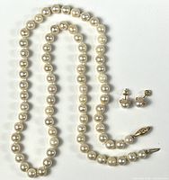 Pearl necklace laid out with earrings beside to show full lot