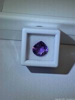 Pear-cut deep purple amethyst in white gem case, front view