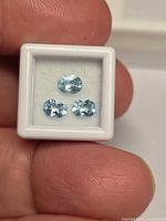 Front view of three oval sky blue topaz stones in display box