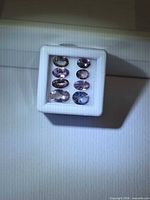 Display box showing multiple views of the oval faceted pink-purple Tanzanite