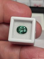 Front view of oval faceted lagoon greenish blue tourmaline in white gem box