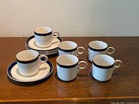 Six espresso cups and five visible saucers showing pattern and overall condition