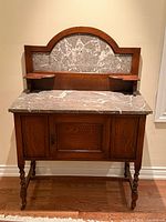 Front view of oak washstand showing marble top, backsplash, shelves, and cabinet door