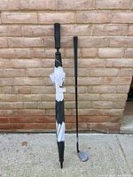Full view of umbrella closed beside golf wedge