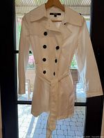 Full view of white DKNY raincoat on hanger showing belt and overall style