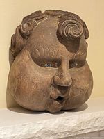 Front view of carved wood mask showing facial details and open mouth