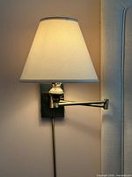 left bedside brass swing arm lamp lit with shade