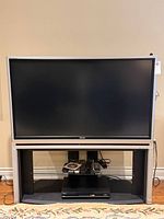 Front view of Toshiba TV on stand with DVD player and remote visible