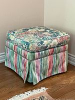 Angled view of ottoman showing floral cushion and striped base