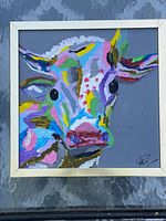 Full view of framed colourful cow painting