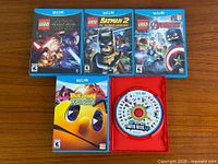 Group shot of five Wii U games including three LEGO titles, Pac-Man title, and Mario disc in red case