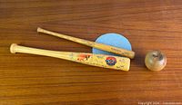 Two mini bats and small wooden ball displayed