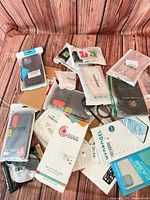 Assorted sealed phone cases, screen protectors and accessories spread on wood surface