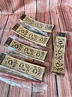 Five ceramic floral incense holders with bundled incense sticks displayed on wood surface