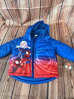 Front view of blue/red Spider-Man puffer jacket with hood and tag visible