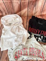All three tops laid out: white hoodie, black Motley Crue tee, grey Santa Monica tee