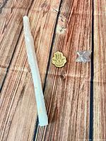Selenite wand, wooden Hamsa token and quartz Merkaba star laid on wood-grain surface