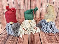 Front view of three burlap-hat gnomes with yarn beards and wooden noses
