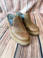 Front three-quarter view of both clogs showing leather uppers and lug soles