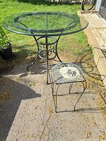 Round glass patio table and smaller side table on driveway