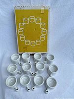 Front view of 13 of the porcelain tealight holders with original Ikea PS box