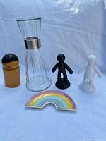 Group shot of all five items: wood grinder, glass carafe, two figurine shakers, rainbow dish