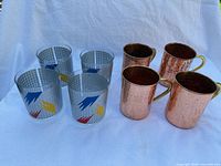 Group view of four acrylic tumblers and four hammered copper mugs