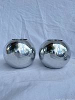two polished stainless steel spherical candle holders front view
