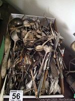 Overview of large box with assorted flatware and serving pieces