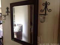 Framed rectangular mirror and two matching sconces mounted on wall, showing overall setup and condition.