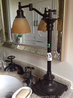 Full view of the metal table lamp next to sink showing base and amber glass shade.