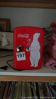 Front view of red Coca-Cola mini fridge showing polar bear holding a Coke bottle, chrome door handle, and power cord.