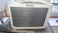 Front view of the Danby air conditioning wall unit with visible vents and attached power cord.