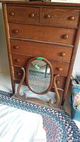 Front view of oak dresser with six drawers and detached oval mirror leaning against it
