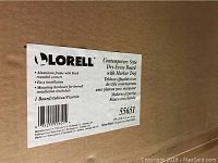 Close-up of Lorell brand label on packaging, showing product details including aluminum frame, black rounded corners, mounting hardware included, and board dimensions (3' x 2').