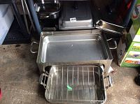 Chafing dish pans and lids stacked together on floor showing different sizes and shapes