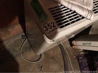 Side view of the white dehumidifier on the floor with power cord visible and inventory sticker #352.
