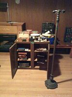 Vintage items including a small wooden cabinet with antique books, a tall decorative metal lamp, and other assorted items on the floor and shelves.